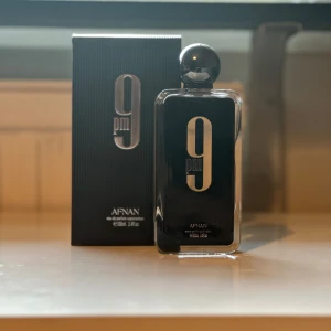 Afnan 9PM Eau de Parfum 100ml - Afnan 9PM är en elegant parfym i en svart, stilren glasflaska med silverdetaljer och rund kork. Flaskan rymmer 100 ml och har en modern, minimalistisk design. Kommer i matchande svart kartong med vertikala ränder och silvertext. Endast testad iprincip full skickar samma dag✅