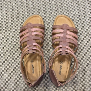 Rosa sandaler från Graceland, strl 36 - Snygga rosa sandaler från Graceland med flera smala remmar och öppen tå. Remmarna har en lätt glittrig finish och sandalerna har en platt sula. Perfekta för varma dagar och ger en cool touch till din sommaroutfit.