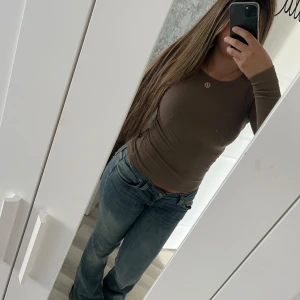 Brun topp - En bekväm långärmad topp som sitter jättefint. Den är mycket strechig och materialet är andningsbart. Den är använd ett fåtal gånger men är sliten vid underarmen. Vid frågor hör av dig!