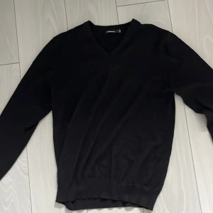 Svart merinoullströja från J.Lindeberg - Svart långärmad tröja från J.Lindeberg i 100% merinoull. Klassisk v-ringning och ribbade muddar vid ärmslut och nederkant. Perfekt för dig som gillar stilrena och enkla plagg med en snygg passform. Ny pris 1400kr