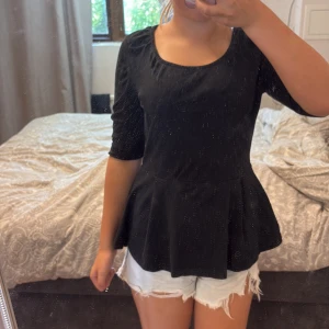 Svart blus med medellånga ärmar och volang neråt - Säljer en svart blus med medellånga ärmar och volang neråt från only