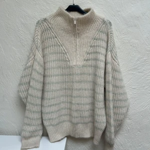 Randig stickad half zip-tröja från MNG - Mysig stickad tröja från MNG i beige och ljusgrön randig design. Oversized passform med lång ärm, hög krage och half zip-dragkedja. Observera att den är stor i storlek, skulle rekommendera denna för en M! Aldrig använd. 