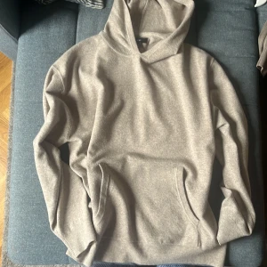 Beige hoodie från NEXT - Säljer en stilren beige hoodie från NEXT i storlek L. Hoodien har en klassisk huva, känguruficka framtill och ribbade muddar vid ärmslut och nederkant. Perfekt för chill dagar och enkel att matcha med jeans eller joggers. Nu pris 500 säljer för 150