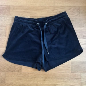 Svarta mjukisshorts från Gina Tricot - Svarta shorts i mjuk frotté med relaxed fit och bred resår i midjan. De har snörning framtill för extra justering och en enkel, stilren look. Perfekta för chill dagar eller när du vill ha något bekvämt och snyggt på sommaren. Från Gina Tricot