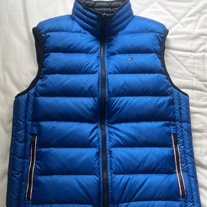 Väst Tommy Hilfiger  - Tommy Hilfiger väst i storlek S. Västen är i mycket fint skick och perfekt till hösten.  Hämtas i Bromma eller frakt på köparens kostnad. Västen har två sidor vilket ger en möjligheten att ha två västar i en.