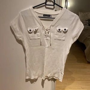 T-shirt - Snygg t-shirt med snörning, fakefickor på brösten och något märke i silvrigt glitter. 