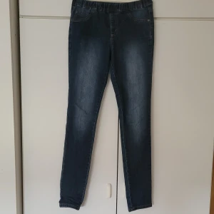 Skinnyjeans - Blåa skinnyjeans från Kappahl i storlek 164, relativt lågmidjade. Längden från midjan  till benets slut är 98 cm. Innerbenslängden är 75 cm. Fejkfickor i fram, men riktiga i bak. Finns ingen dragkedja eller knappar, endast dra på o av! 