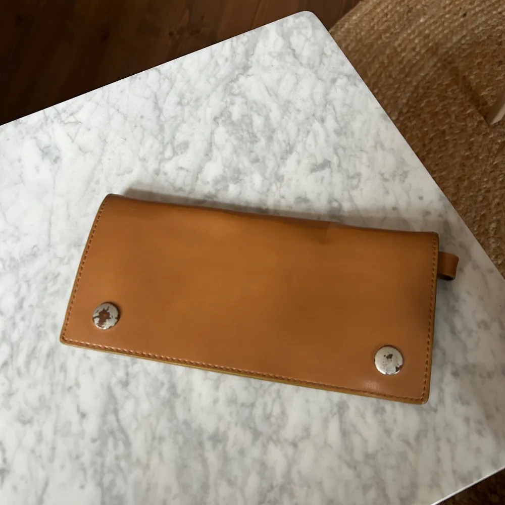 Kan också användas som kuvertväska. Ljusbrun plånbok i läder från Acne Studios som man också kan ha som kuvertväska. Skav på knapparna (se bild) annars i kanonskick.. Accessoarer.