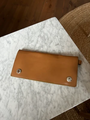 Acne vintage plånbok i skinn - Kan också användas som kuvertväska. Ljusbrun plånbok i läder från Acne Studios som man också kan ha som kuvertväska. Skav på knapparna (se bild) annars i kanonskick.