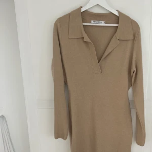 Stickad Adoore klänning - Säljer en beige stickad klänning från Adoore som passar perfekt till hösten. Formar kroppen på ett smickrade sätt. Storlek 40.