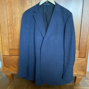 Mörkblå kavaj - En mörkblå snygg kavaj i väldigt bra skick från dressman. Säljer den då den är för liten. Svarta chinos på köpet!