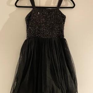 Glittrig tyllklänning  - Svart, glittrig tyllklänning från Lindex 