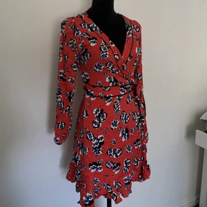 Röd Blommig Klänning  - Röd Blommig Klänning från BikBok. Så otroligt fint och sitter jätte bra. Knytning runt midjan. Nyskick. Lite skrynklig på bilden men det är bara att stryka! Säljer pga inte min stil längre! 