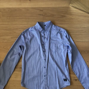 Skjorta örjan andersson - Blå-vit randig skjorta från Örjan Andersson strl M, något glansig i tyget. 