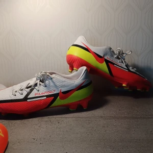 Fotbollskor  - Fotbollskor Nike Phantom GT använd fåtal ggr helt fräscha/ny.Köpt för 999kr. Storlek 42, väldigt bra kvalitet🔥.Benskydd ingår med skorna.Köpt Benskydd köpt för 200 kr,namn Protouch 800 Orange/gul.Allt är rengjort.Pris 260kr för allt. Skosnöre oxå nya