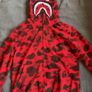 Bape hoodie - En full zip hoodie från A Bathing Ape i storlek L, säljer för jag inte andvänder längre. Priset kan diskuteras, och skriv till mig om du vill ha bevis på att den är äkta, den har till exempel ”golden bape tag” som jag kan skicka bild på för bevis.