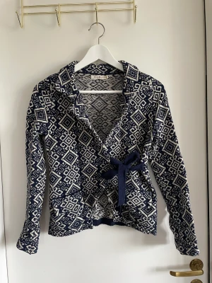 Mönstrad kofta med knytning - Mönstrad kofta med knytning tvärs över. Fickor på sidorna.