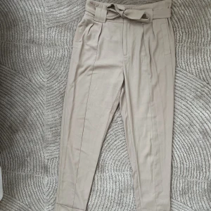 Kostymbyxor  - Byxor i storlek 34 men passar en 36 också.   Fästet till knappen är trasig, men sys lätt fast igen. Se 3de bilden.