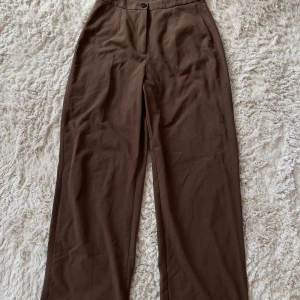 Kostymbyxor  - Jättefina bruna kostymbyxor, säljs på grund av de är för korta för mig. L men  kan användas som M beroende hur man vill att den ska sitta  