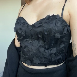 Topp - Jättefin svart topp med blommor i jättefint skick. Endast använd 1 gång. Korsettliknande topp. Storlek 36.  Nypris 699