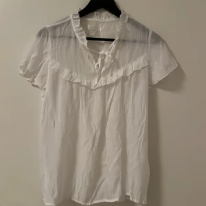 Blus med volang - Kortärmad luftig blus i tunt material. Använd flera gånger. 