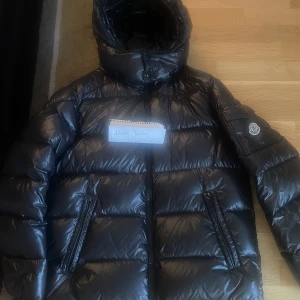 Moncler Maya Size 4 - Moncler Maya Black Down Jacket, använd sparsamt i två vintrar. Inga skador eller liknande. I size 4 vilket motsvarar M/L i vanliga storlekar KVTITTO FINNS!
