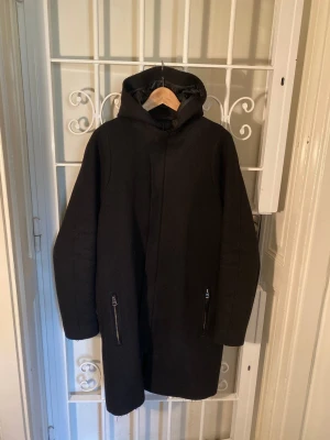 Acne Studios – Milton Parka - Svart Acne Studios Milton Parka. I fint skick.  Storlek: 50.  Yttertyg: 100 % ull. Foder: 100 % polyamid. Fyllning: 100 % polyester.  Litet hål på ena ärmslutet som enkelt kan sys (se sista bilden).  Hämtas i Stockholm, Vasastan. Eller skickas.