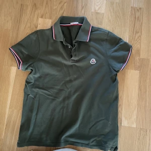Moncler Piké Mörkgrön - Säljer min moncler piké I storlek S, den är inköp för ungefär 12 månader sen på nk hemsida, kvitto finns. Kan tänka mig att gå ner i pris vid snabb affär😊