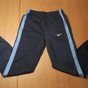 Nike mjukisbyxor  - Ett par Nike mjukisbyxor med dragkjedja på sidorna av benen som går upp typ 25cm. Väldigt bra skick och knappast använda.