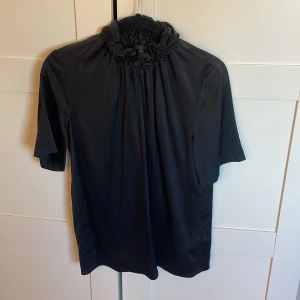Svart blus COS - Snygg svart blus från COS i jätteskönt material med en liten krage 