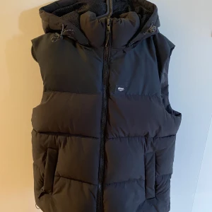 Svart dunväst med luva - Tjena! Säljer min svarta dunväst med en avtagbar luva i storlek S. Använd ett fåtal gånger så skicket är 9/10, som nytt. Vid frågor eller funderingar är det bara att skriva.