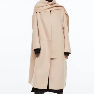 Kappa - Säljer min jättefina beigea kappa från h&m. En oversized fit med slitsar på vardera sida. Tillkommer en tillhörande halsduk!  Ord.pris 1299kr. I jättefint skick!