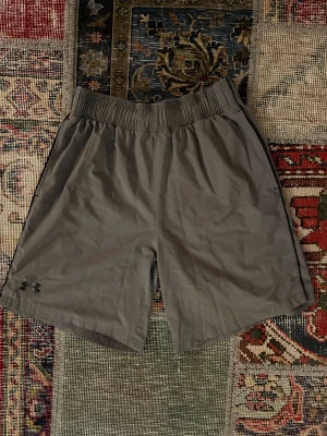 Under Armour Träningsshorts - Säljer dessa gråa Under Armour träningsshorts i storlek medium med en skön loose fit passform. Perfekta för träning eller en avslappnad dag. De är i fint skick och väntar på en ny ägare!