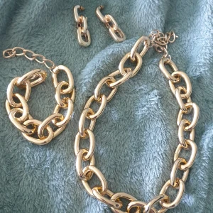 Guldfärgat smyckesset  - Köpt från bubbleroom , halsband armband örhängen . Lättviktigt. Vet ej material 