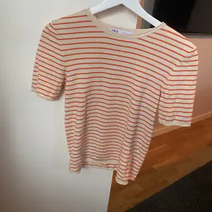Gräddvit/Orange randig t-shirts från Zara. Använd fåtal gånger. Liten i storleken! 