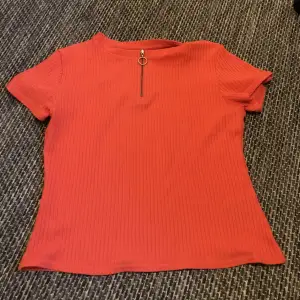Ljusröd ribbad t-shirt från H&M i storlek M (tycker den sitter mer som en S dock). Dragkedjan går att dra ner beroende på hur man vill styla. 20kr + 30kr frakt :)