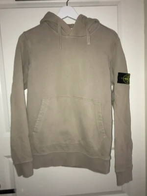 Stone Island Hoodie Beige Stl. XS - Säljer denna SI hoodie eftersom jag vuxit ur den. Den är köpt på tradera för ca 1 år sedan. Den har inga defekter.