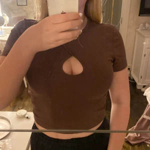 Topp - En brun ribbad kroppad topp med ett tillgjort hål vid brösten. Nytt skick nästan aldrig använt.