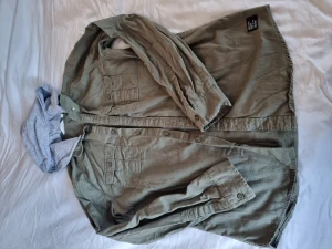 Skjorta - Grön skjorta med grå luva som går att ta bort. Tryck på ryggen. Storlek 170