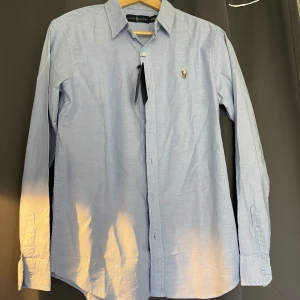 Helt oanvänd Ralph Lauren skjorta, ljusblå! - Skjortan är helt ny oanvänd, säljer den pga storleken! Lappar finns kvar! 