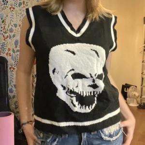 Stickad väst med döskalle - Svart varm väst med döskalle. Bra skick. Snygg över vit blus eller sådant !