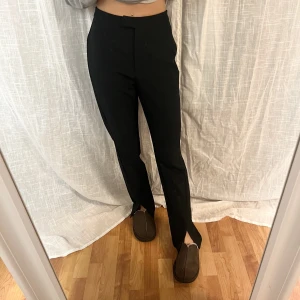 Kostymbyxor med slit - Kostymbyxor från NA-KD i storlek 34, dem är mid waist och har slit fram vid fötterna. Säljer då jag beställde fel storlek och inte orkade skicka tillbaka 
