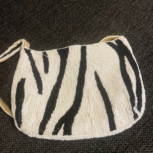 pärlig zebra axelväska - jätte söt zebramönstrad axelväska av pärlor. i bra skick, den enda defekten är att bandet har lossnat lite som man kan se i sista bilden💕