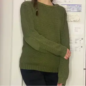 En lite tjockare stickad tröja i en mossgrön färg 
