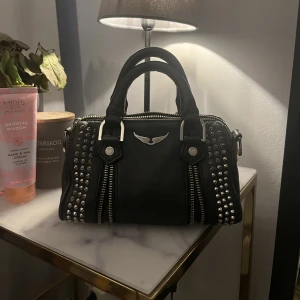 Zadig väska! - Säljer min fina zadig väska. Köptes på plick i september inga defekter eller något utan bra skick dock är den lite rostig på dragkedjan. Har även ett band till som man får med.