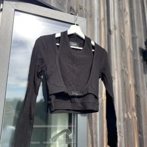 Långärmad tröja Cider. HELT NY - Cool tröja med spänne under bysten. Innerdelen träs över huvudet och skapar illusionen av ett linne. Mycket mjukt och stretchigt tyg🖤  !!Helt ny!! Nypris: 250kr Säljes pga fel storlek och missade skicka tillbaka i tid. 