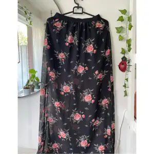 Säljer denna supersnygga svarta långkjol med rosa blommor från H&M i stl 34. Den består av två lager, med en kort svart kjol och en tunnare blommönstrad långkjol över. Perfekt för sommaren! Fint skick✨ Skriv om du har frågor :)