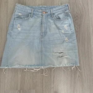 Jeanskjol - Blå denim jeanskjol från H&M, slitningar på låret, knappt använd 