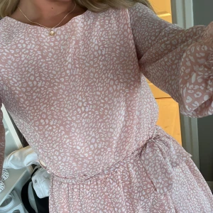 Rosa klänning  - Rosa klänning med blommor och band med justerbar midja, storlek s