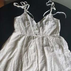 Vit klänning  - Aldrig använd, jättesöt vit klänning, till studenten kanske? Dubbla tyglager.  Knytband på axlarna, dragkedja i sidan.  Storlek L men passar M med mindre byst. 
